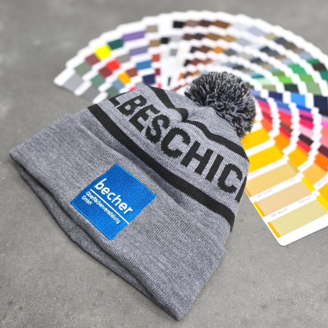 Graue Pudelmütze bestickt mit blauem Firmenlogo Handwerksbetrieb