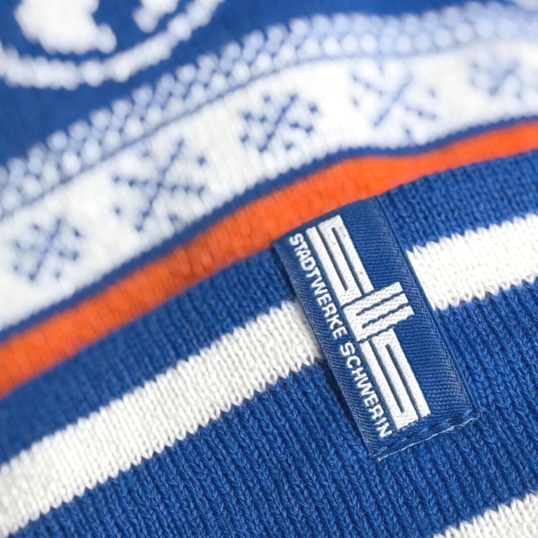 Gewebtes Label mit Stadtwerke-Logo am Umschlag einer Mütze mit Sternen-Design