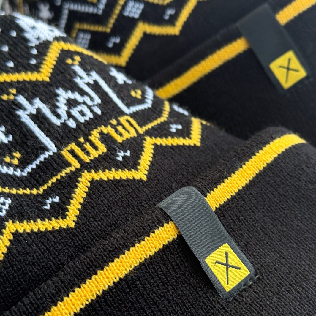 Schwarze Mützen Agentur mit gelb-weißem Weihnachtsdesign und gewebten Logo-Labels