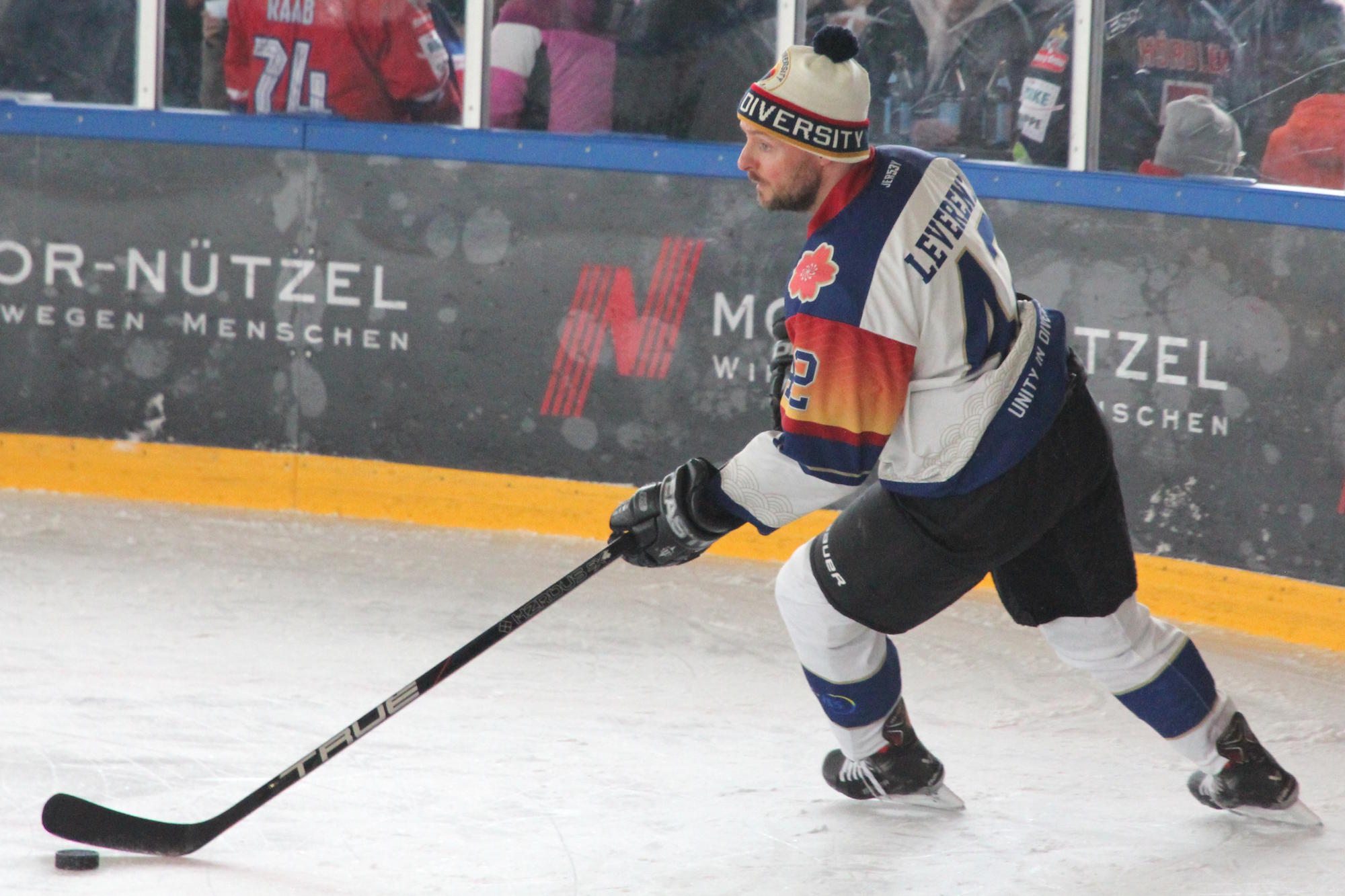 Eishockeyspieler mit Mütze führt den Puck