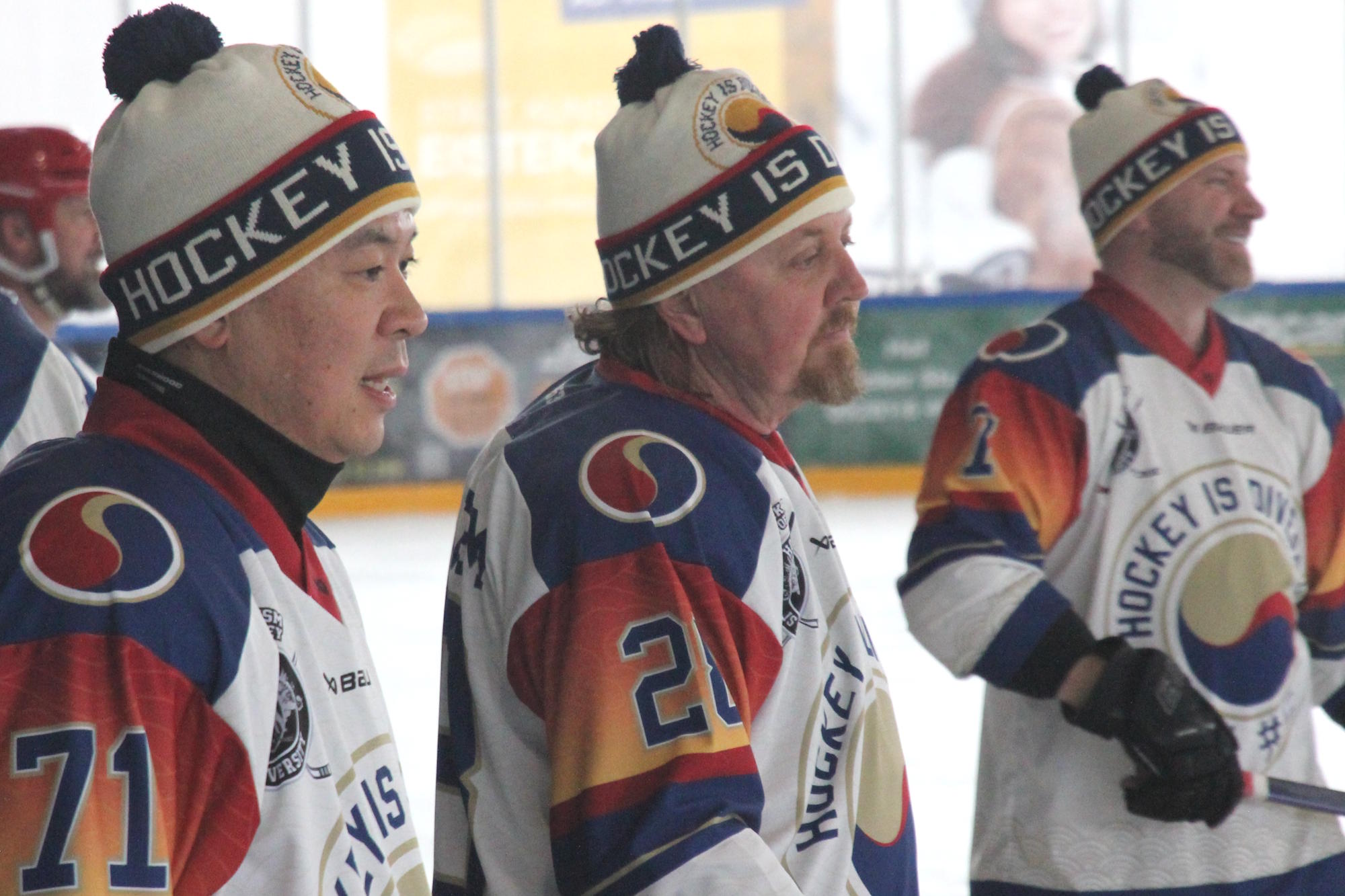 Drei Eishockey-Spieler tragen Teammmützen beim Warm-up